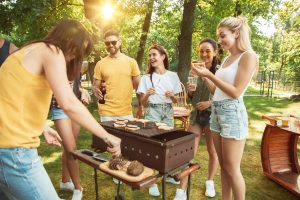 Groep vrienden heeft plezier, lachen en zijn aan het barbecuen op een mooie zomerse dag.